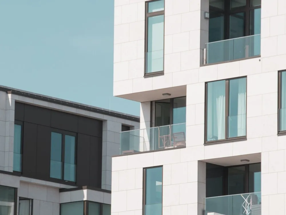 Gedung apartemen putih dengan balkon kaca