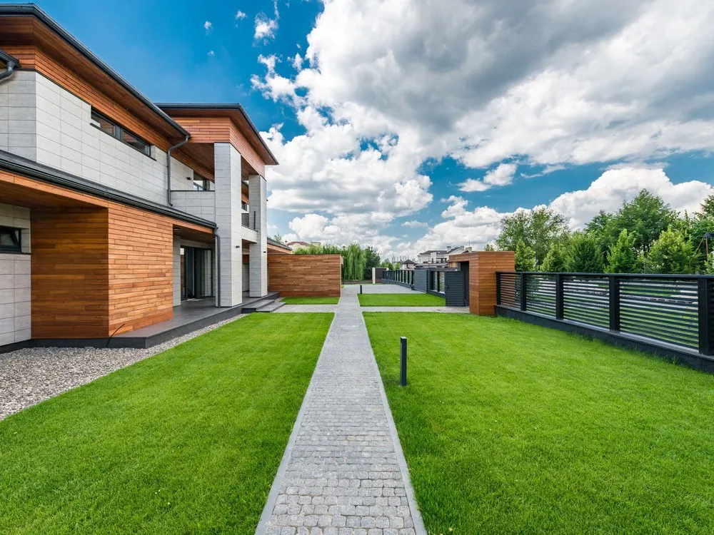 Rumah modern dua lantai dengan halaman rumput dan jalan setapak